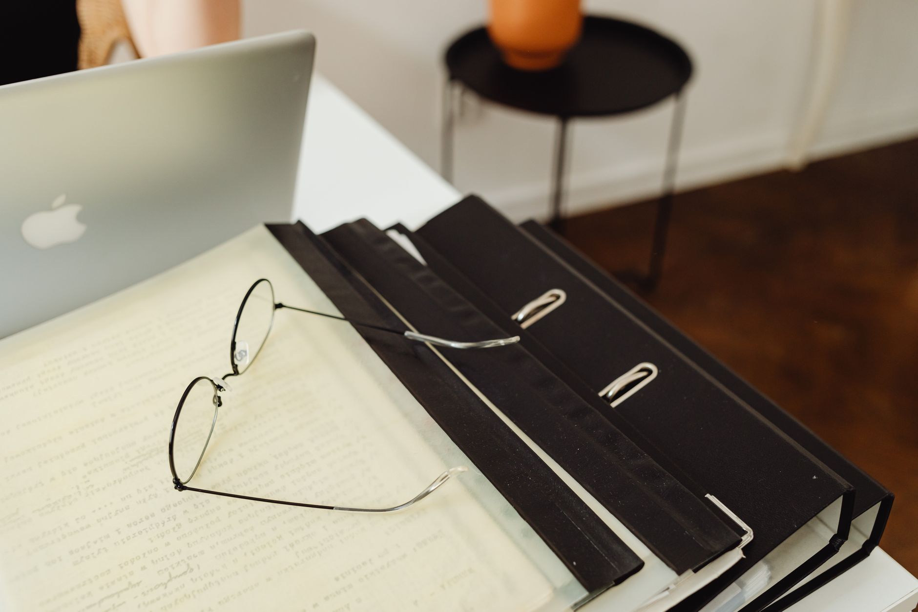 A neat office setup with binders, eyeglasses, and a laptop, perfect for productivity.